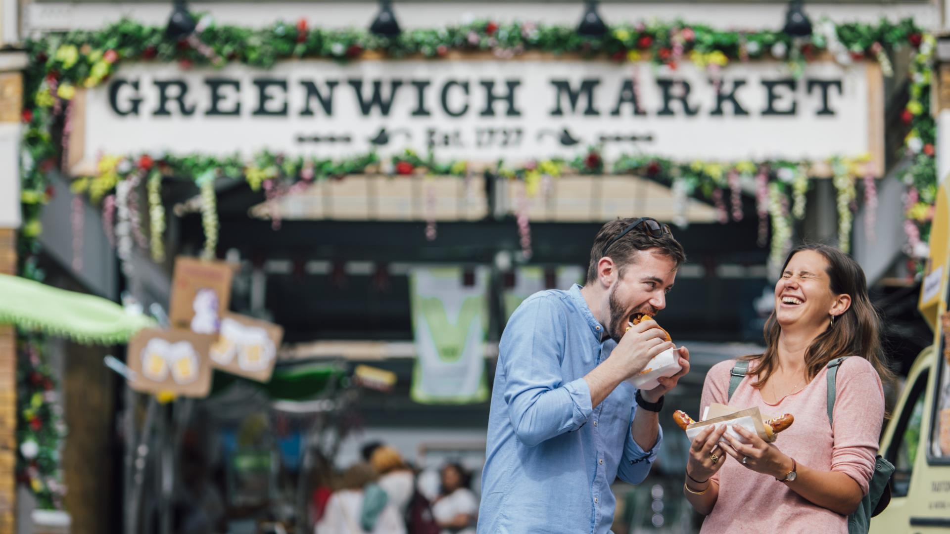 A couple eat food from the Food Court at Greenwich Market.