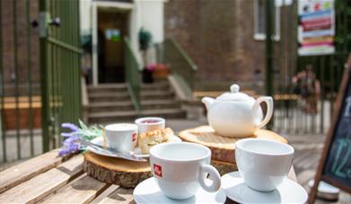 A teapot and teacups laid out on a table outside Severndroog Castle in the sunshine.