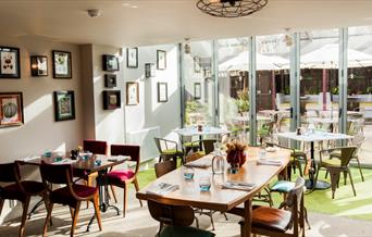 The dining room at The Pilot is bright and airy and overlooks the garden through floor to ceiling glass doors.