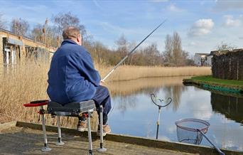 A person fishing by the lake at Tump 53 in Thamesmead
