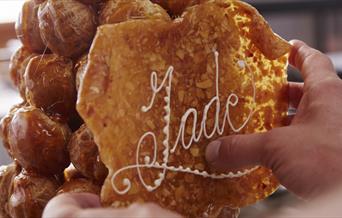 In the image, the Jade Boulangerie pastry chef is adding a display with 'Jade' written to the stack of profiteroles.