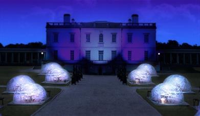Night view of the Queen's House with eight Dining Domes set on the grounds in front of the art gallery.