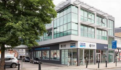 Outside the front of Oxford international education group in Greenwich. showing a square shaped building with lots of windows.