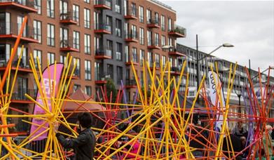 Everyone is invited to play their part in creating a huge structure from wooden rainbow coloured sticks.