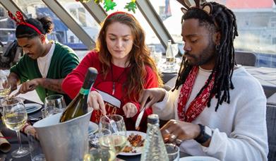 Christmas Day lunch cruise in London. A festive setting with people enjoying a three course meal.
