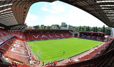 Image shows players in action inside the stadium with red seating all round.