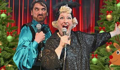 two people singing karaoke in Woolwich with Christmas trees in the background