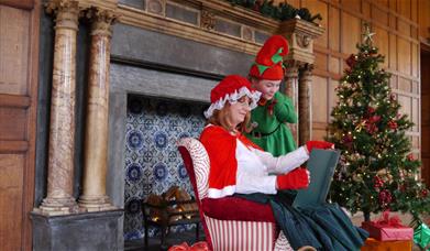 Mrs Claus telling a story in a nice decorated room with an elf.