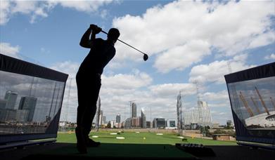 A golfer hits a golf ball at Greenwich Peninsula Golf Driving Range.