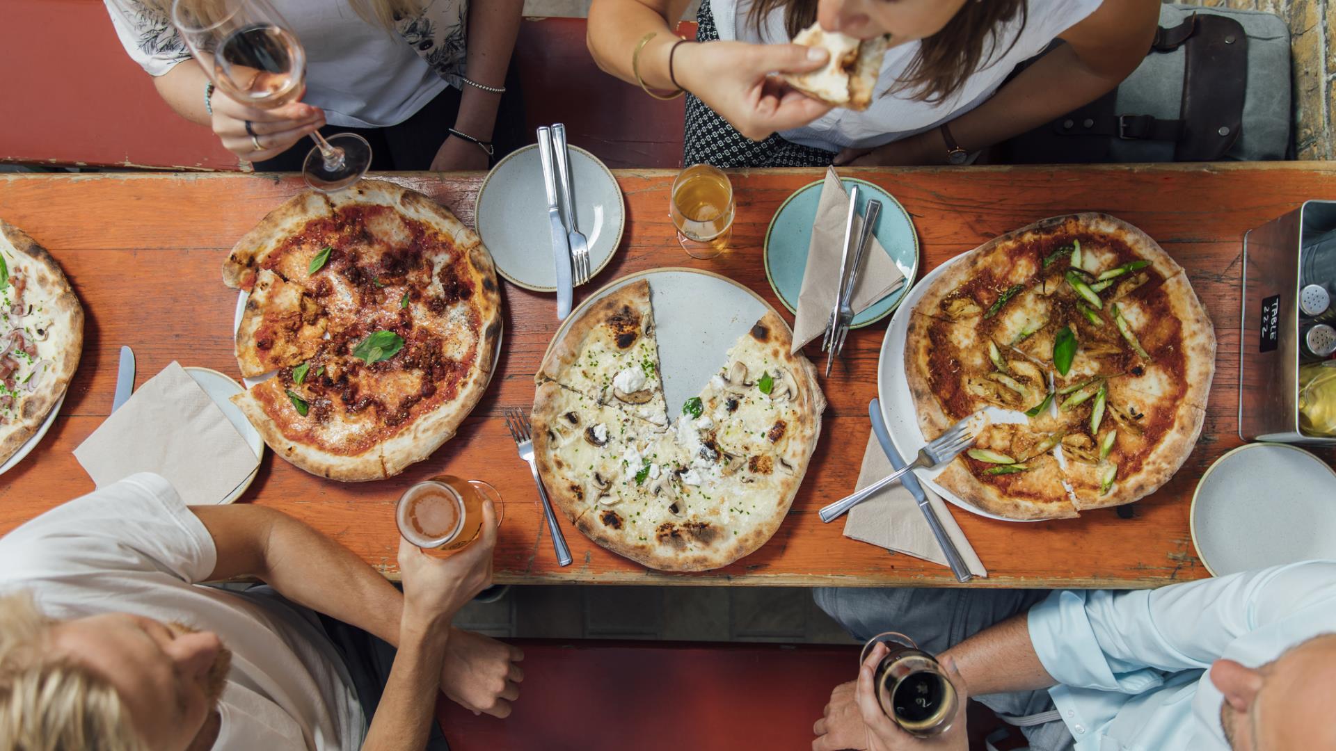 A group of friends eating pizza and sharing a few drinks at the Taproom in Woolwich Arsenal.