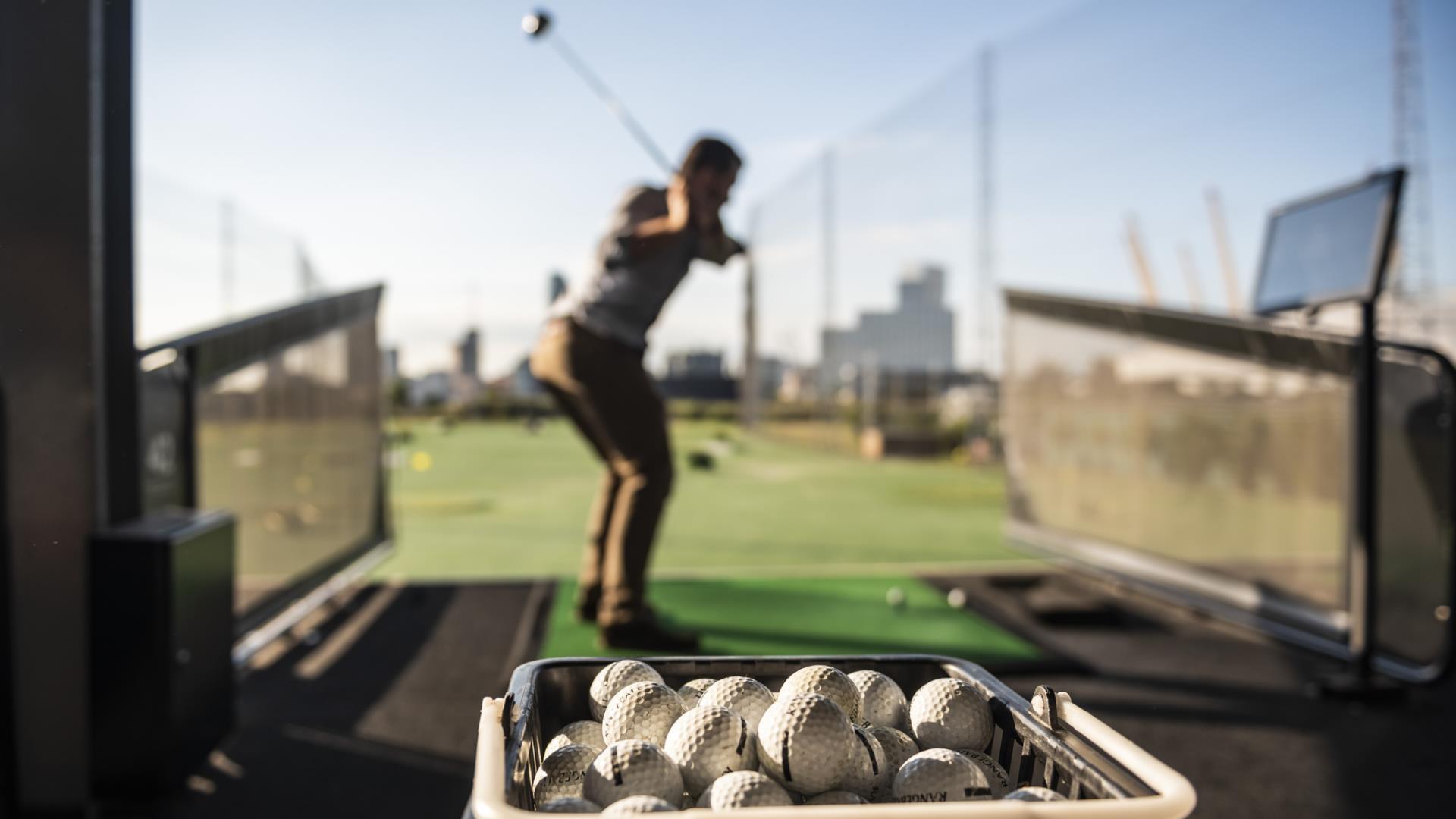 A man takes a swing at the Greenwich Peninsula Golf Driving Range.