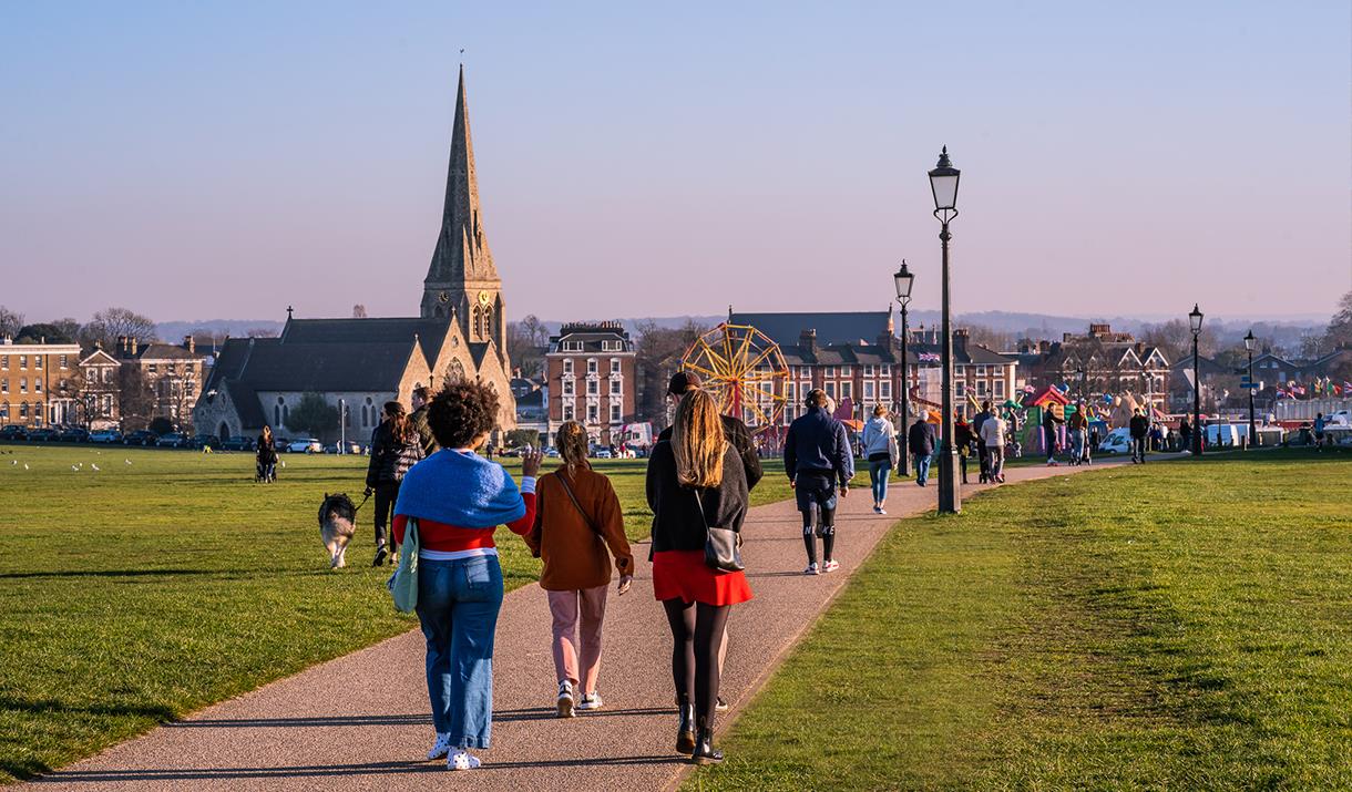 Friends and families walk across the beautiful Blackheath common towards All Saint's church and the fun fair.