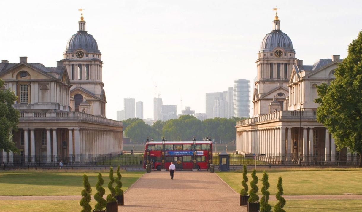 A London Bus centre aligned between Old Royal Naval College domes in Greenwich looking toward the river Thames in Greenwich