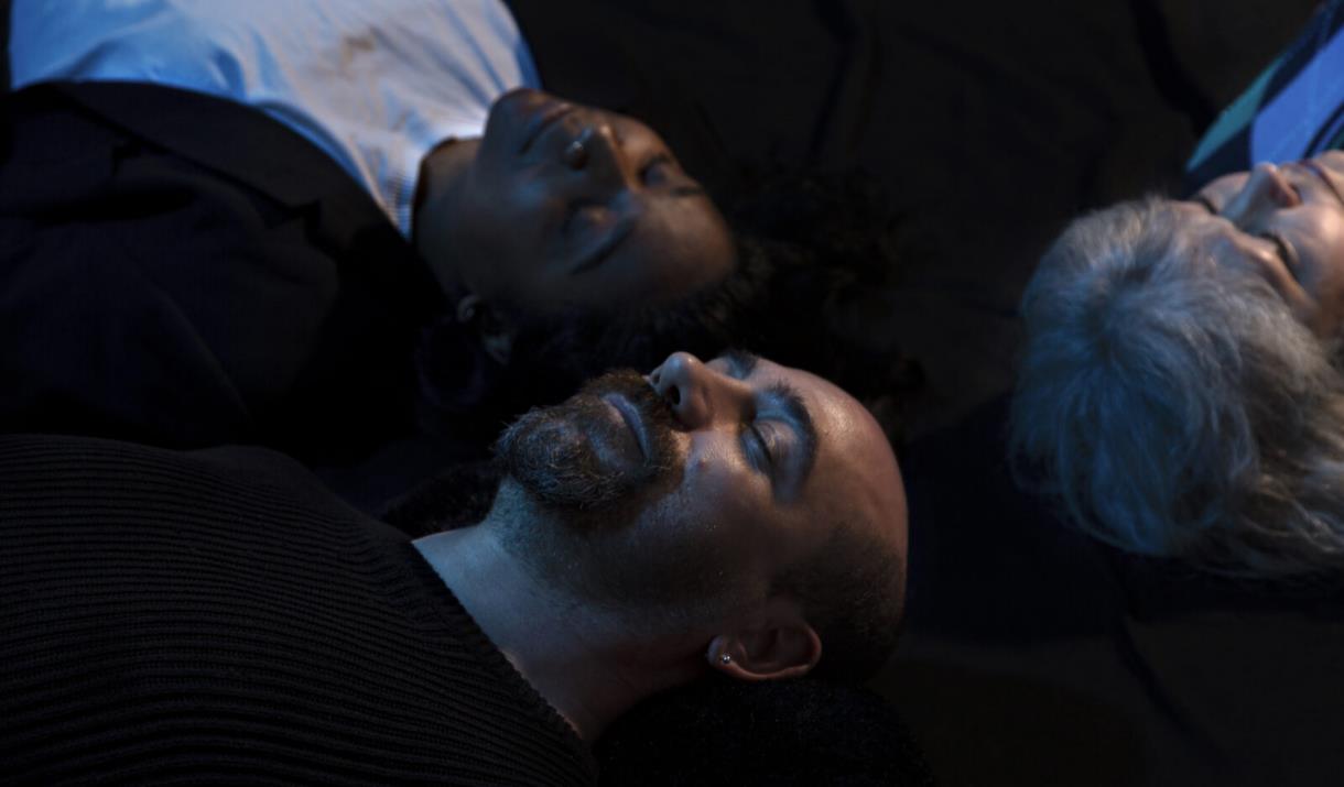 Three people lying down in the darkness at Dreamachine in Woolwich.