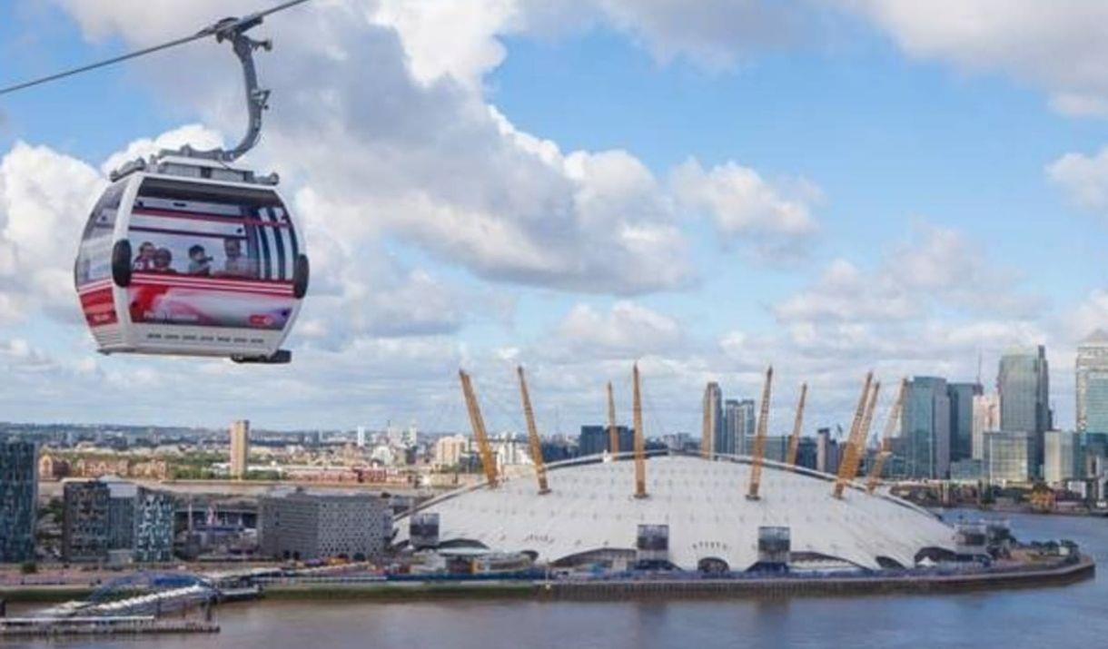 Emirates Air Line Cable Car soaring over the river Thames at dusk, overlooking The O2 and Canary Wharf