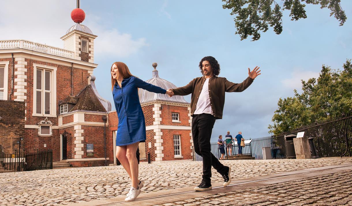A couple hold hands on the Meridian Line at the Royal Observatory