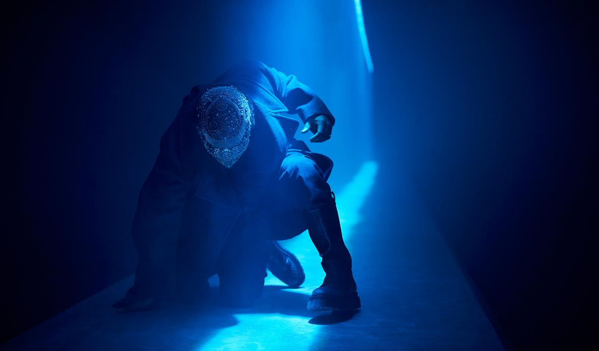 Live performance in action with neon blue light shining on a performer in the Troy World at The Burnt City