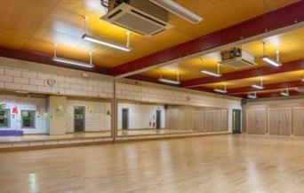 Inside one of Thamesmere Leisure Centre's fitness halls, showing a brown room with mirrors, good lighting and air conditioning.