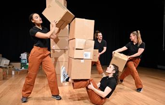 Group of people dancing with and around cardboard boxes