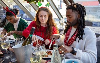 Christmas Day lunch cruise in London. A festive setting with people enjoying a three course meal.
