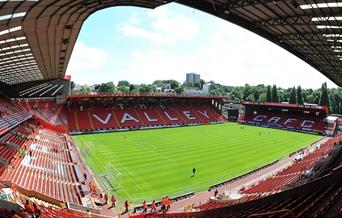 Image shows players in action inside the stadium with red seating all round.