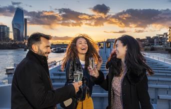 People enjoy a drink on City Cruises at sunset