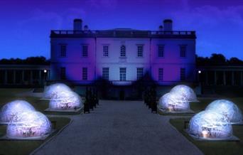 Night view of the Queen's House with eight Dining Domes set on the grounds in front of the art gallery.