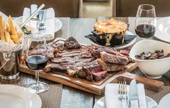 A delicious table of food including steak, chips and mac n cheese served to perfection at Manhattan Grill.