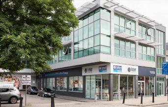 Outside the front of Oxford international education group in Greenwich. showing a square shaped building with lots of windows.