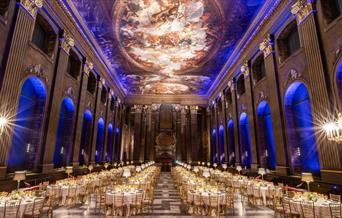 white banqueting round tables setup in the Painted Hall for formal dinner with blue lighting