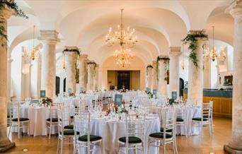 white banqueting round tables and dressed columns for a formal dinner at the Queen Mary Undercroft, Old Royal Naval College