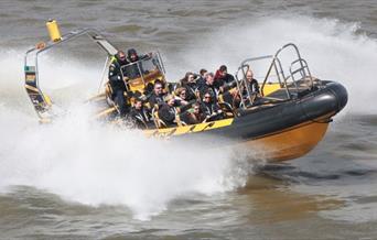 Black and yellow Thames RIB speedboat in action on river Thames.