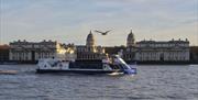 City Cruises boat on river Thames with Old Royal Naval College in the background