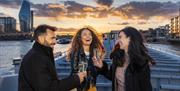 People enjoy a drink on City Cruises at sunset