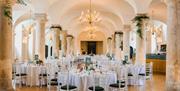 white banqueting round tables and dressed columns for a formal dinner at the Queen Mary Undercroft, Old Royal Naval College
