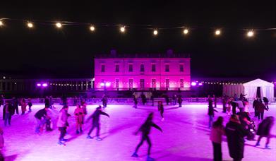 People skating in an illuminated ice rink in front of  Queen's House in Greenwich