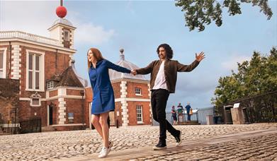 A couple hold hands on the Meridian Line at the Royal Observatory