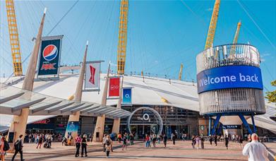 The O2 dome in white covering with 5 yellow stands visible and large glass door entrance