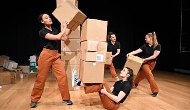 Group of people dancing with and around cardboard boxes