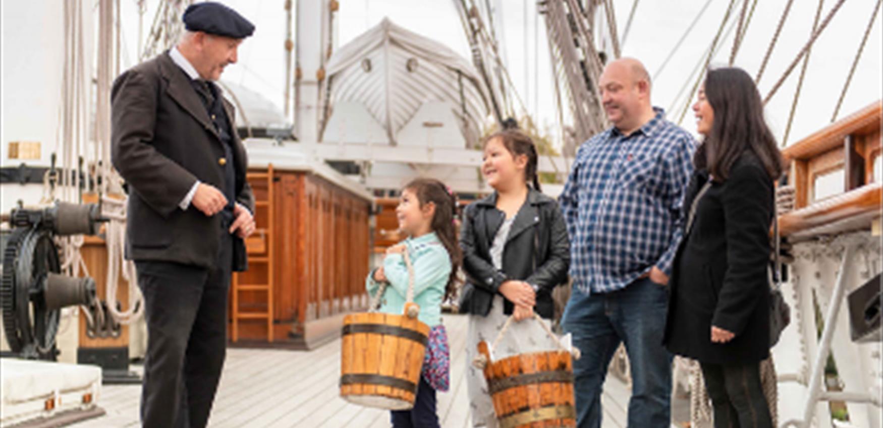 A family speak to the captain of the Cutty Sark in Greenwich.