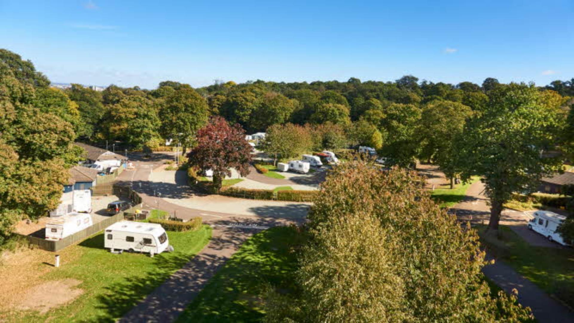Tents and caravans nestled amongst beautiful green trees in Abbey Wood Caravan and Camping park, Greenwich.