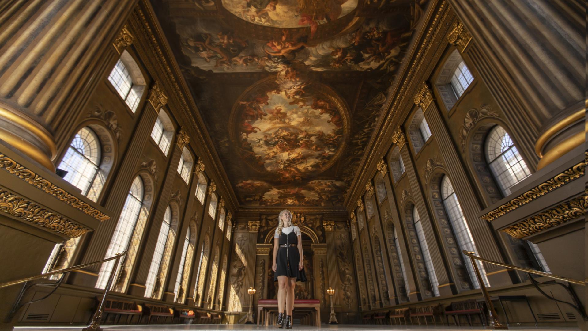 A woman stands in the middle of the huge Painted Hall at the Old Royal Naval College in Greenwich.