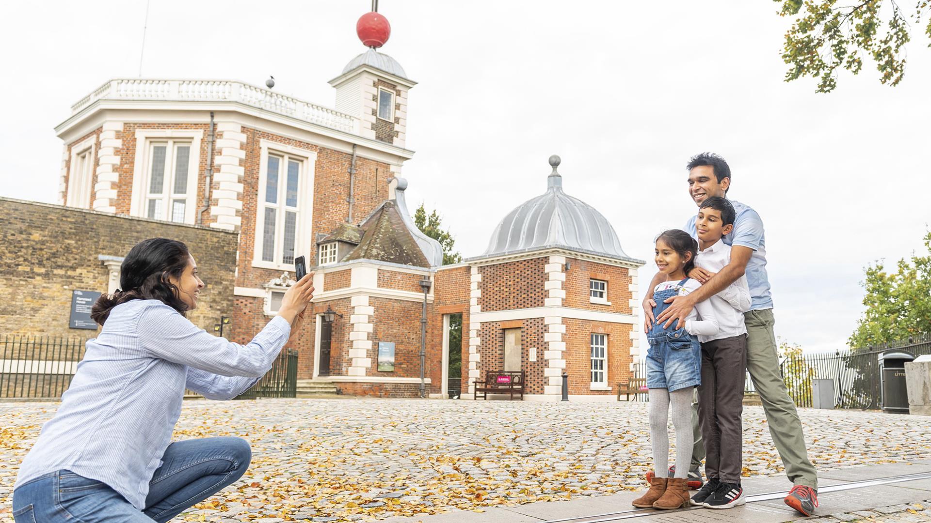 A family have their photo taken while posing on the Meridian Line at the Royal Observatory in Greenwich.