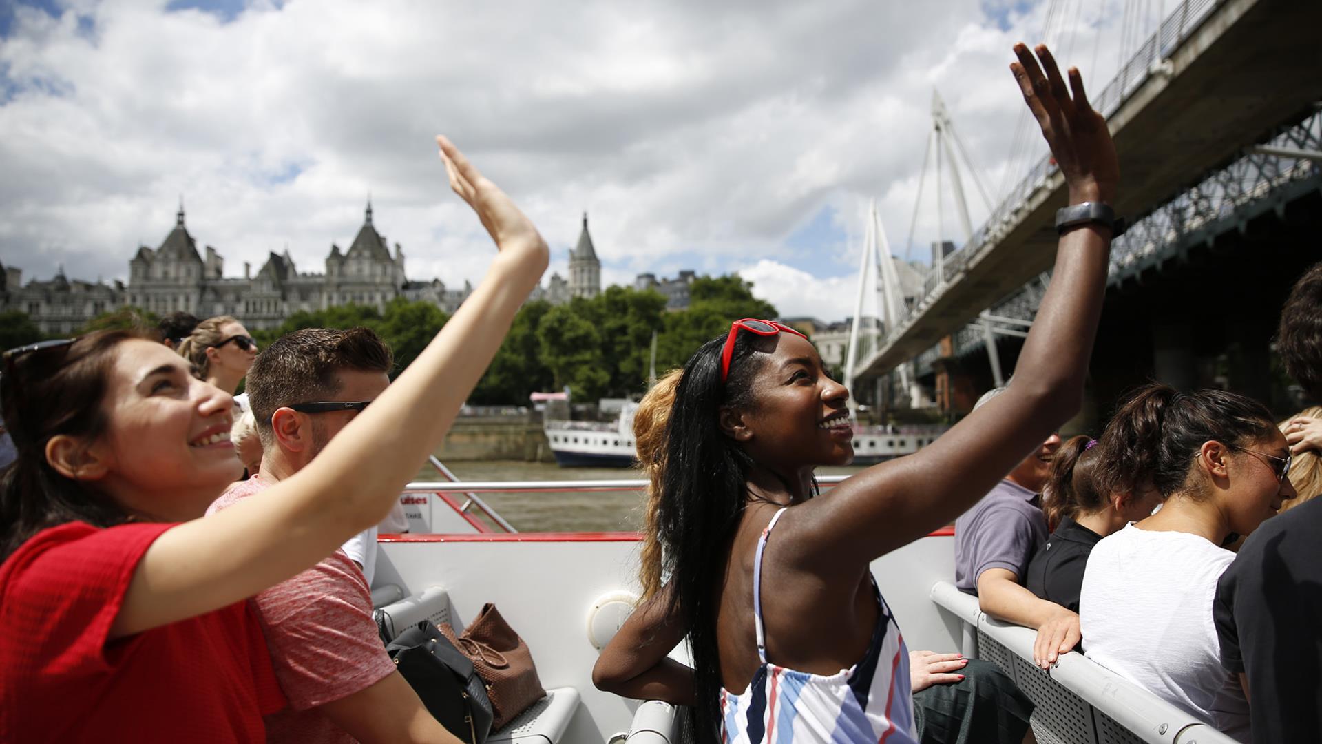 A group of girls wave at passers-by from the top deck of a City Cruises boat.