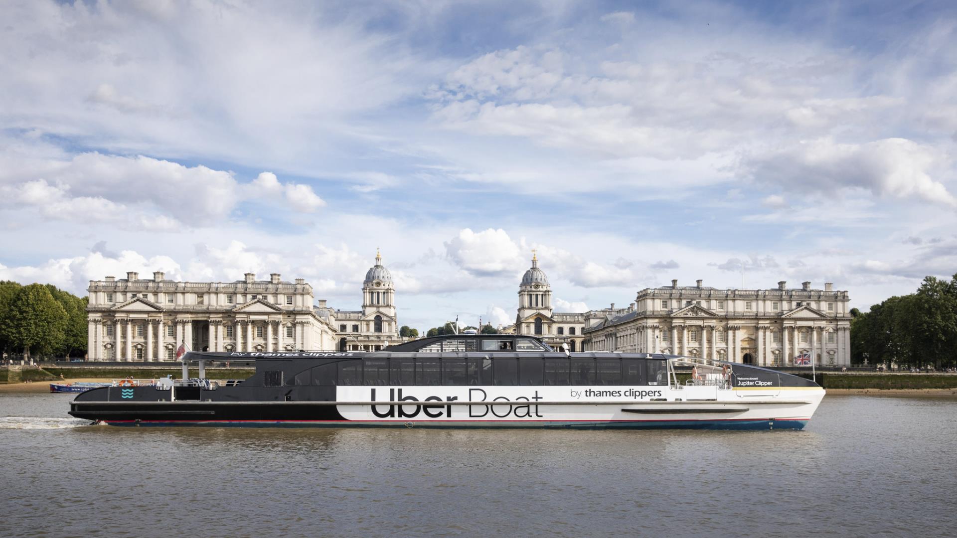 An Uber Boat by Thames Clipper floating past the Old Royal Naval College from the North Bank of the River Thames