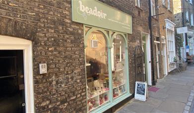 Outside Beadoir in Greenwich. This picture shows a welcoming shop painted mint green and a lovely indoor area.