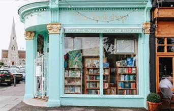 Outside The Bookshop on the Heath in Blackheath. A mint green painted bookshop with a white gate and windows showing a wide range of books.