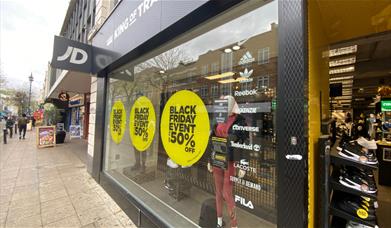 Outside JD Sports in Woolwich. A black, white and yellow themed shop with a great selection of items.