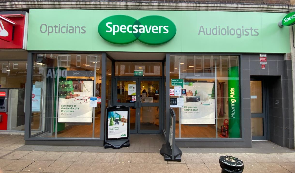 Outside Specsavers, showing a pale green shop front with a lovely inside area.
