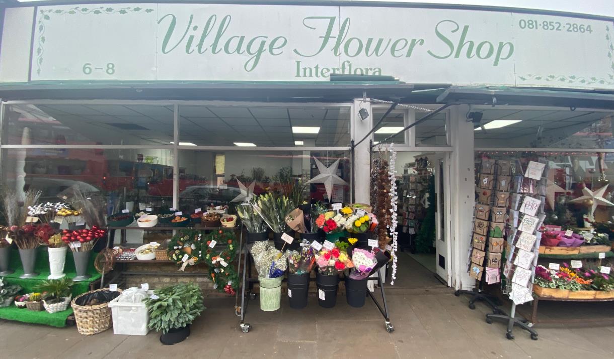 Outside Village Flower Shop in Blackheath. Showing a Green and White Themed Shop with Multiple Rows  of Stunning Flowers.